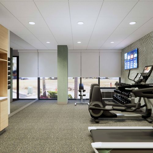 A modern gym with treadmills, a rack of dumbbells, and a wall-mounted TV, featuring a bright and clean design.