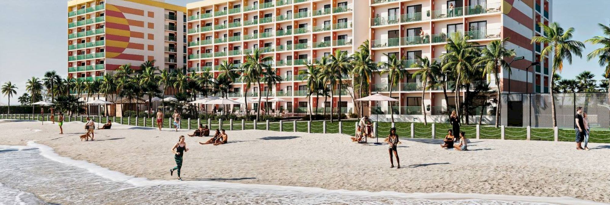 A beachfront hotel with colorful architecture, palm trees, and people enjoying the sandy beach by the ocean under a clear blue sky.