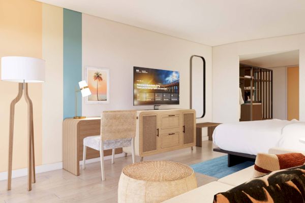 A modern hotel room with a TV, desk, chair, bed, floor lamp, and artwork. Decor features light wood tones and colorful accents.