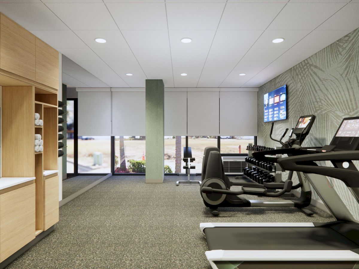 The image shows a modern gym with treadmills, dumbbells, a wall-mounted TV, and a refreshment area with towels.